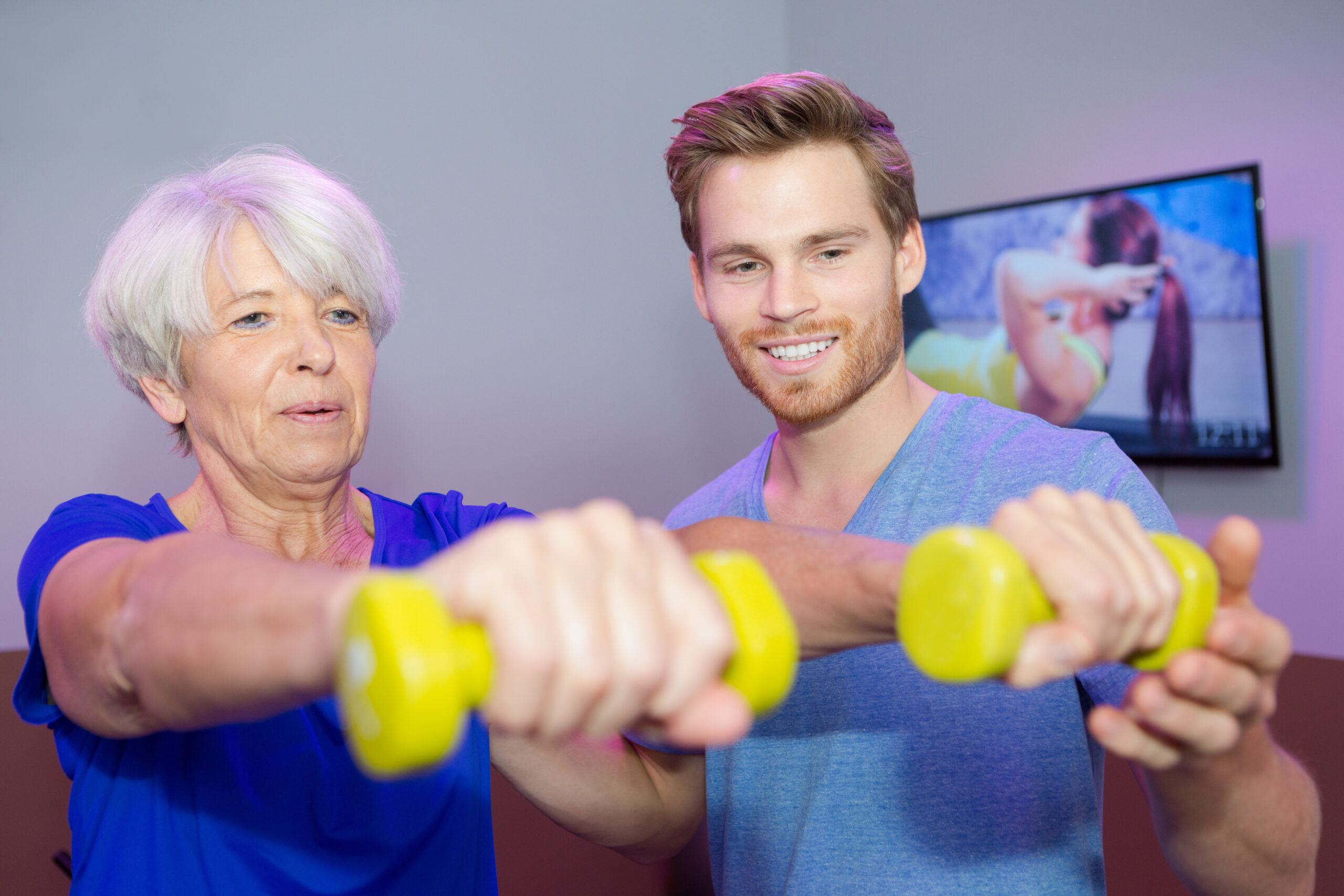 male coach with senior woman with dumbbells